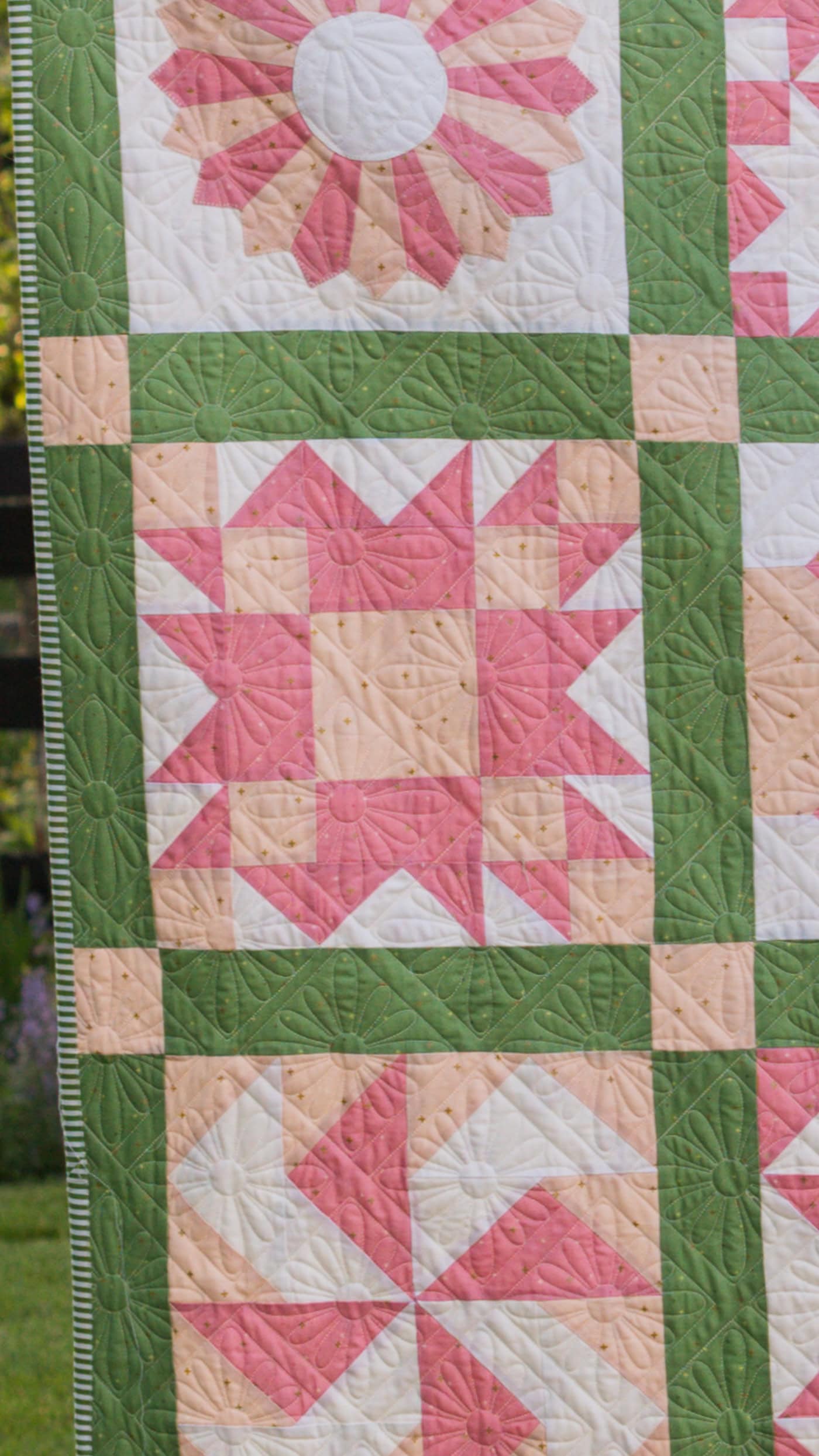 pink and green sampler quilt outdoors