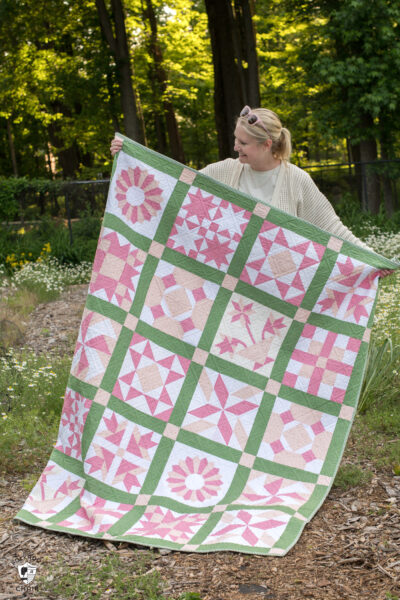 woman holding pink and green vintage quilt outdoors