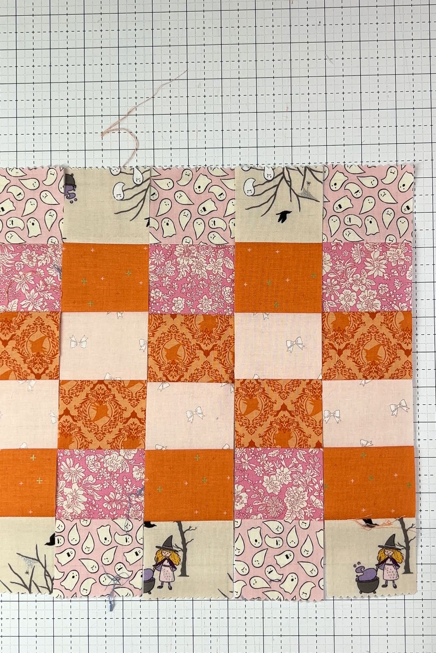 orange, pink and ivory strips of fabric being cut with rotary cutter and ruler