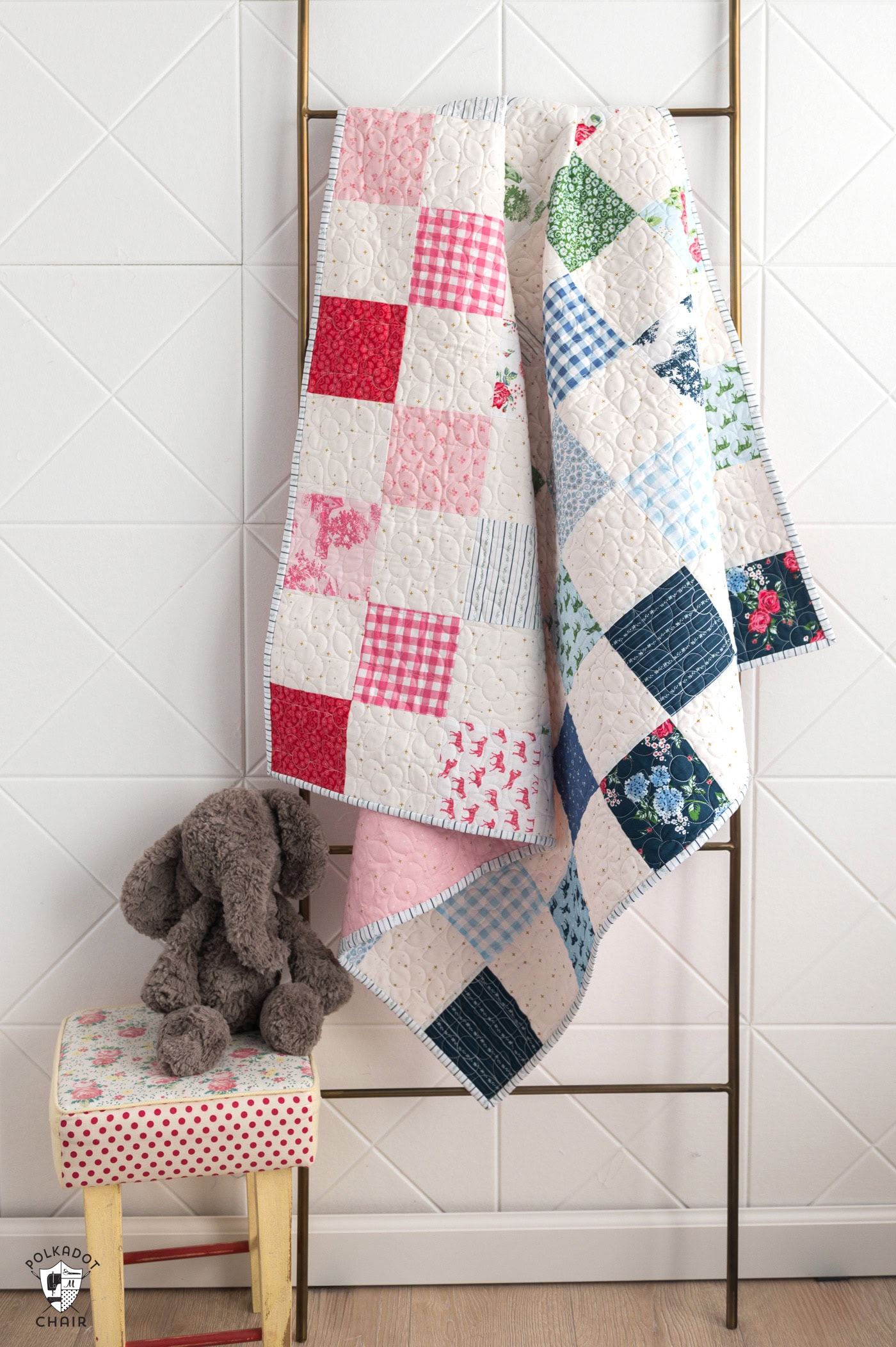 patchwork quilt in white and blues, greens and pinks hanging on quilt ladder