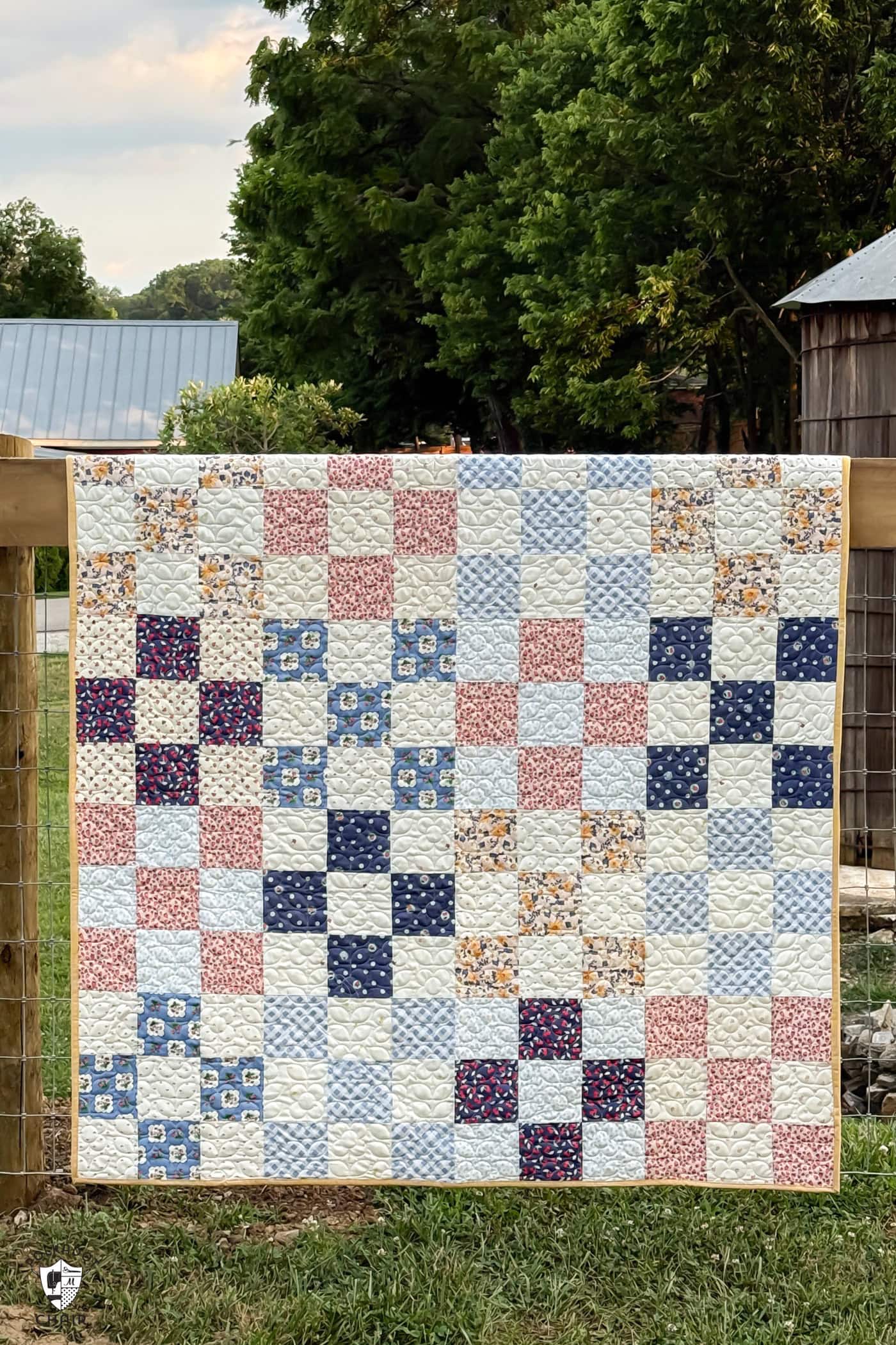 patchwork quilt hanging on old fence