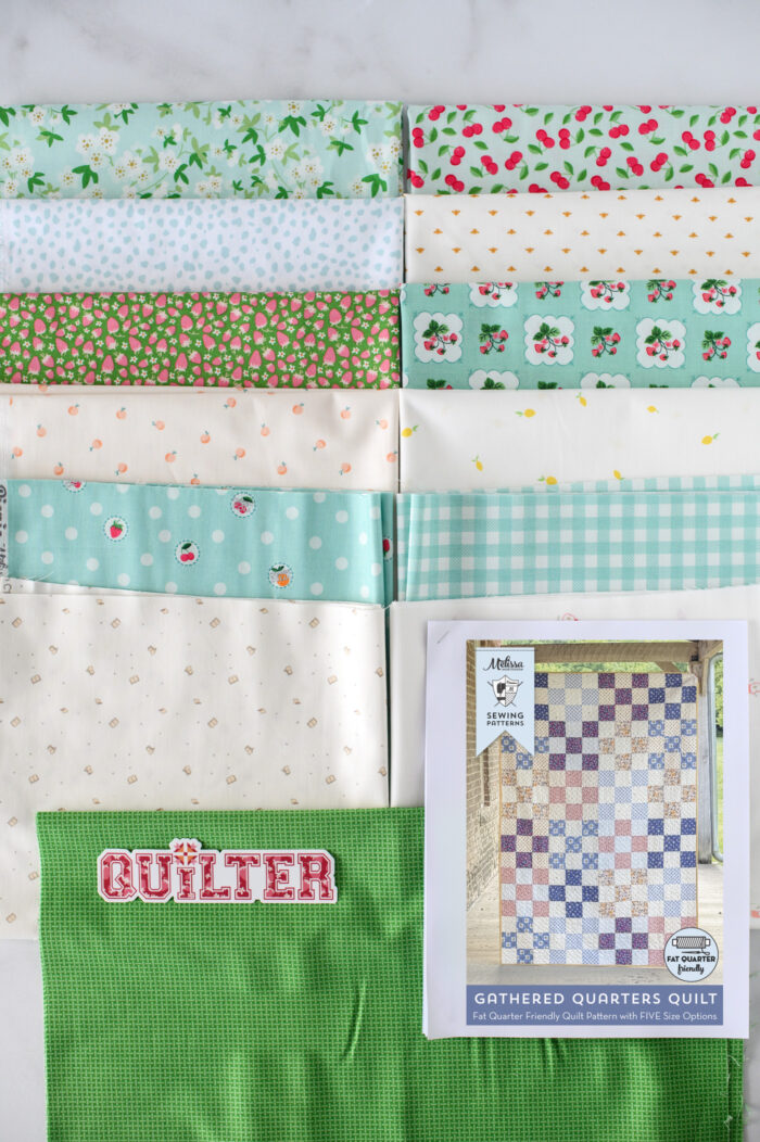 stack of fabrics on cutting mat, aquas and greens
