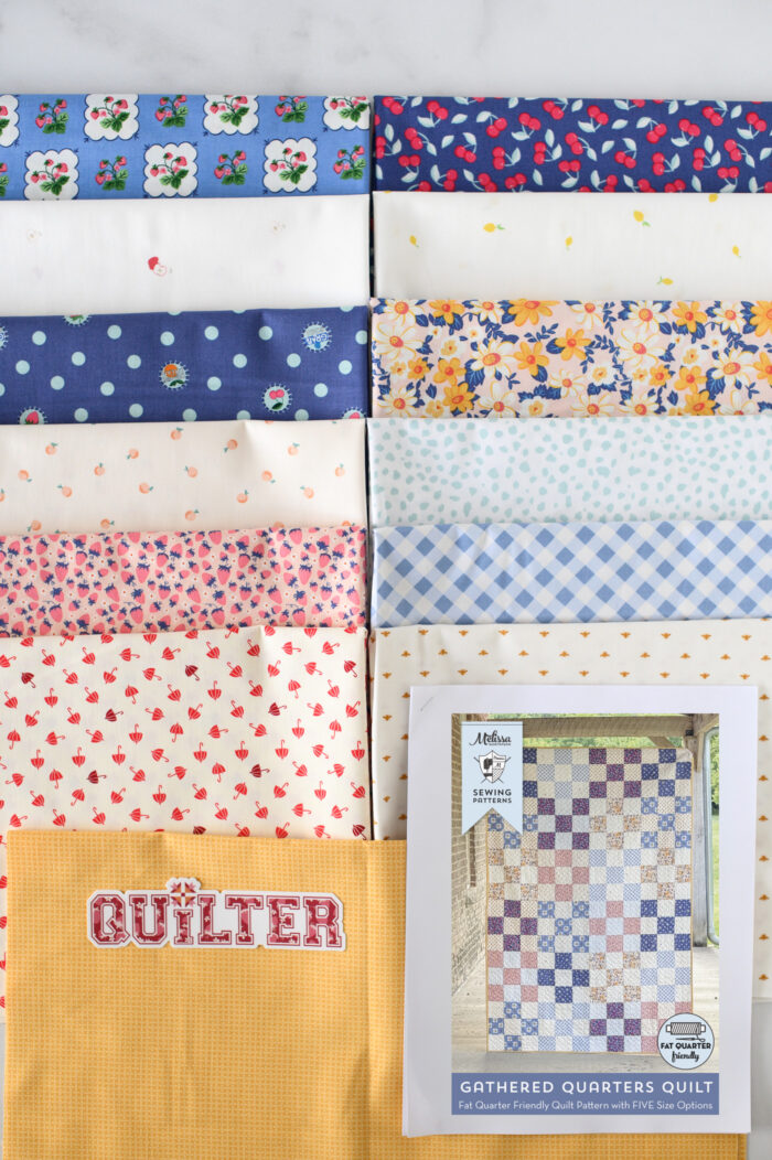 stack of fabrics on cutting mat, blues, pinks and yellows