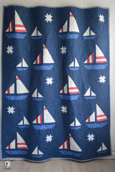 navy blue sailboat quilt hanging on wall in room