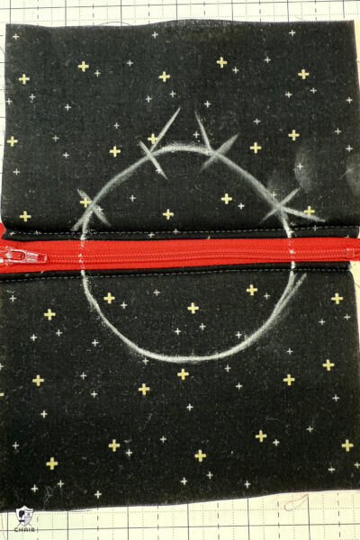 black fabric on cutting mat with red zipper showing construction steps of zip pouch