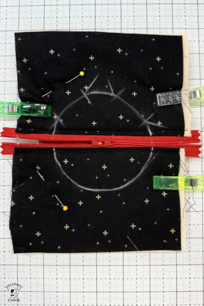 black fabric on cutting mat with red zipper showing construction steps of zip pouch