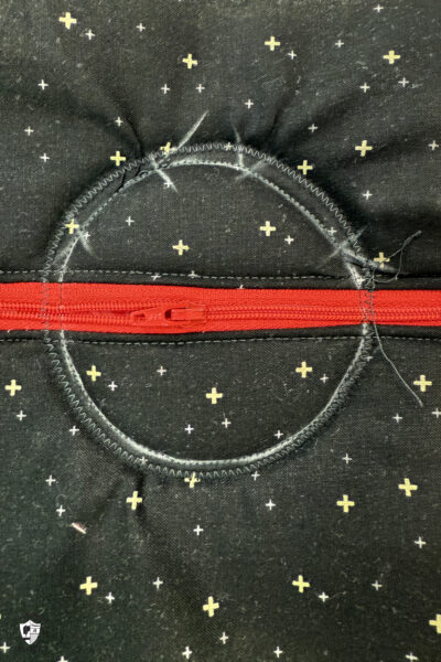 black fabric on cutting mat with red zipper showing construction steps of zip pouch