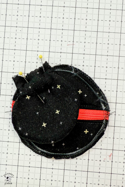 black fabric on cutting mat with red zipper showing construction steps of zip pouch
