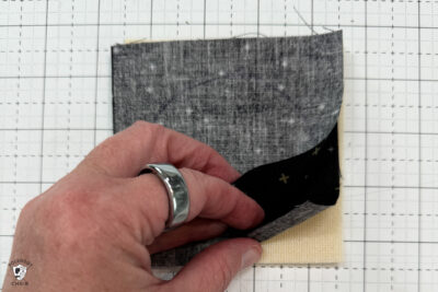 black fabric on cutting mat showing construction steps of zip pouch