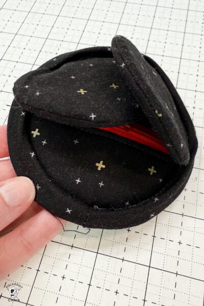 black fabric on cutting mat with red zipper showing construction steps of zip pouch
