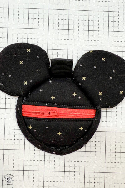 black fabric on cutting mat with red zipper showing construction steps of zip pouch