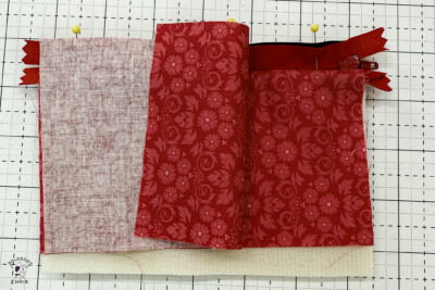 black fabric on cutting mat with red zipper showing construction steps of zip pouch