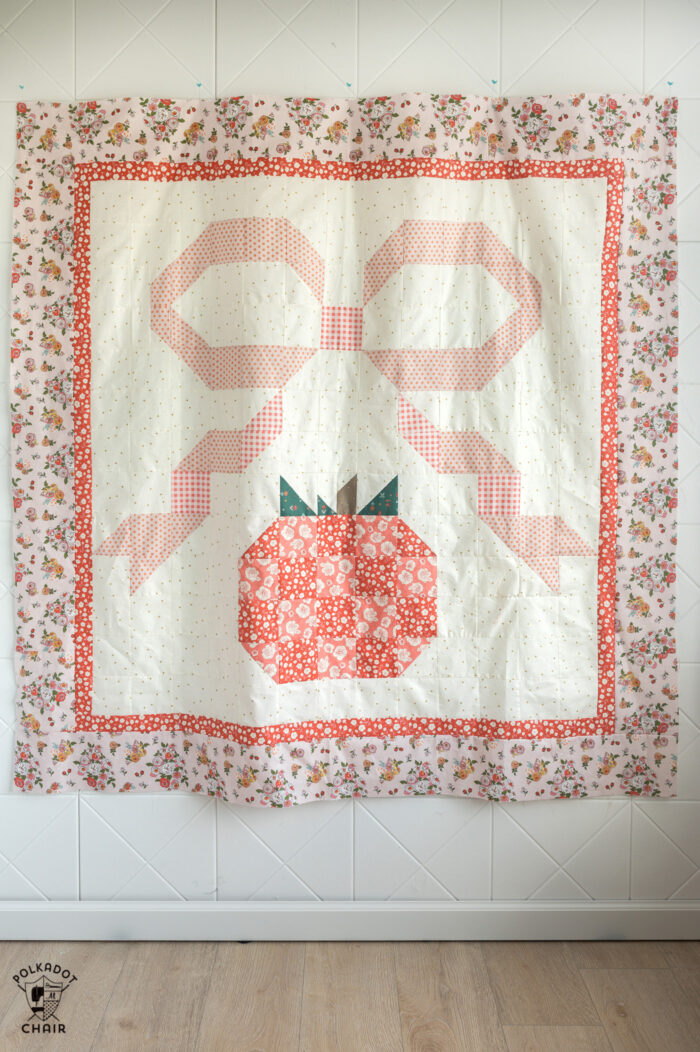 ivory and coral pumpkin quilt hanging on wall