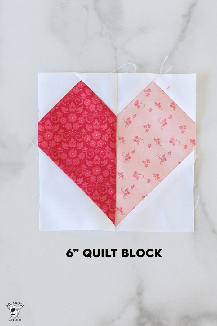 Pink and white heart quilt block on white table