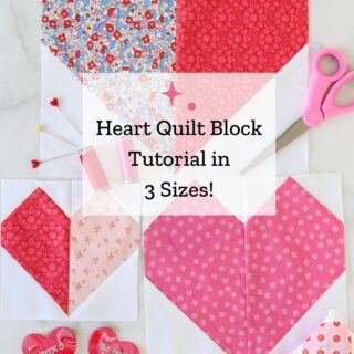 Three heart quilt blocks in pink, red and white on white table with sewing notions