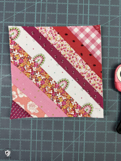 string quilt block sewn and trimmed on blue cutting mat