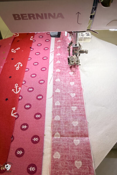 fabric strips on paper under sewing machine foot