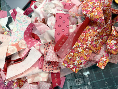 strips of red and pink fabric on cutting mat