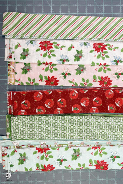 stacks of christmas fabric cut on cutting table