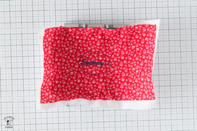 Red polka dot pillow with Sydney logo on a grid background.