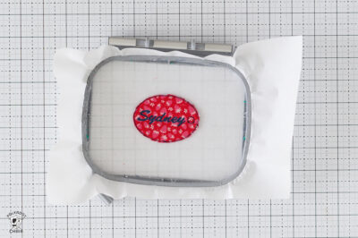 Red and blue embroidered patch with name 'Sydney' on white background.