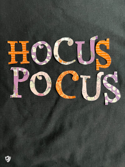close up of Hocus Pocus Halloween letters on black sweatshirt
